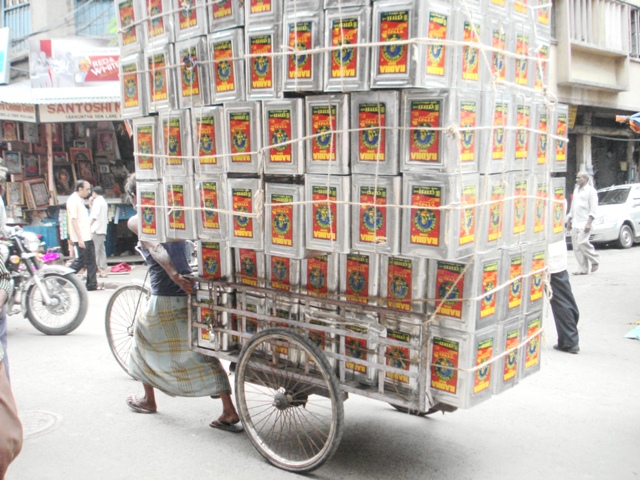 Another hand-pulled rickshaw with tons of oil tins!